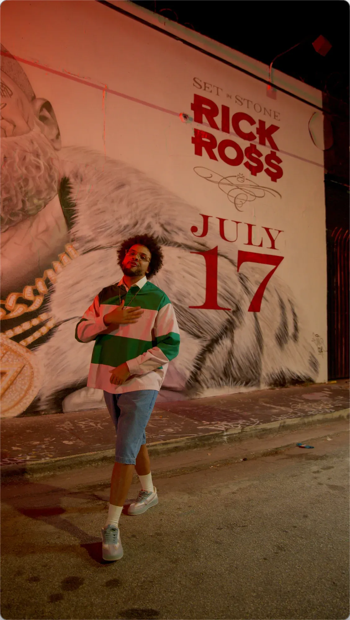 XLEONDUZ standing full length in front of the red-lit Rick Ross mural and July 17 lettering.